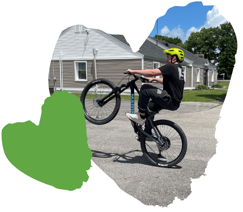 student doing wheelie on bicycle outside of Spaulding residence buildings