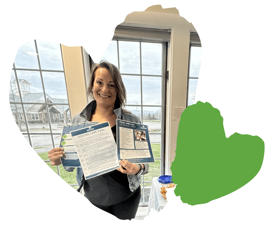staff member smiling and holding foster care pamphlets