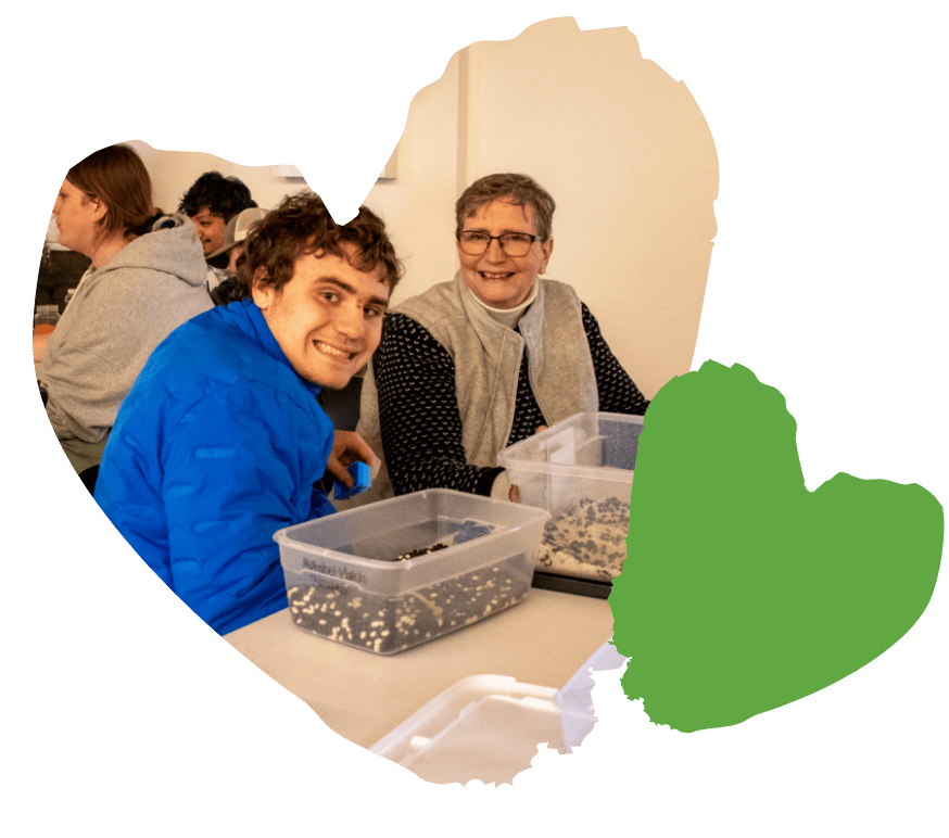 Two people smiling at a table, collaborating on a project with containers of materials.