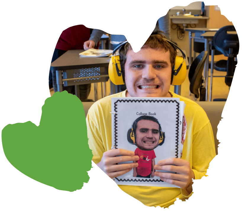 student smiling while showing off collage book he made
