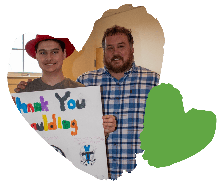 student smiles and holds hand drawn poster that reads "thank you spaulding"