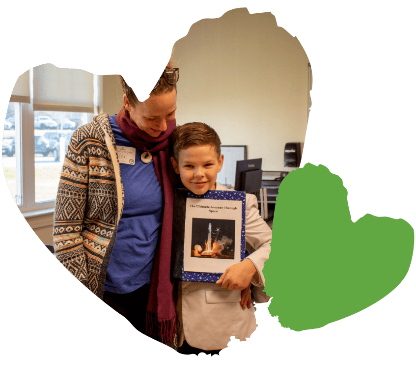 student posed with his mom while showing off book he wrote at school