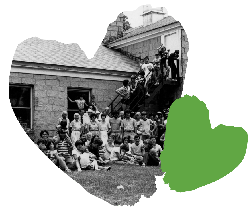 A group of people gathered outside a Spaulding's old building, some sitting on stairs, with a green heart overlay.