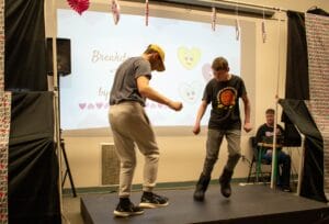 Two boys dancing on a small stage, with a Breakdance slide displayed in the background.