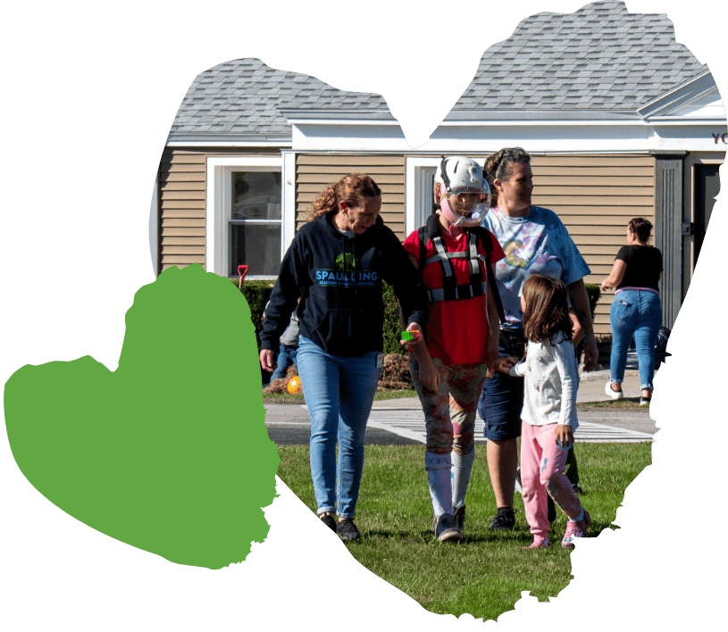 A group of people strolling on the grass, including one in a helmet, with a heart graphic overlay.