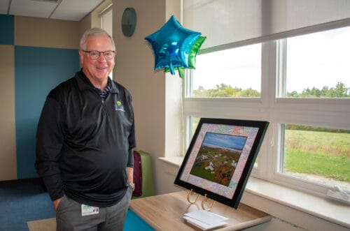 Smiling man stands by a window with star-shaped balloons and a framed photo on a table. Smiling man stands by a window with star-shaped balloons and a framed photo on a table.