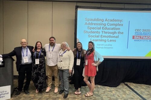 Five people pose in front of a conference screen about social emotional learning for special education students.